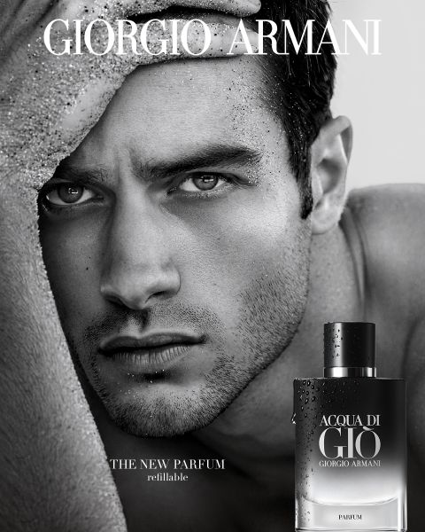 Eine Schwarzweiß-Werbung für Giorgio Armani zeigt die Nahaufnahme eines Mannes mit Wasser im Gesicht neben einer Flasche Acqua di Giò-Parfüm. Der Text lautet: „Giorgio Armani. Das neue Parfum. Nachfüllbar.“.