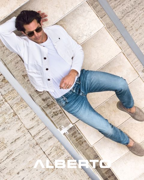 Ein Mann mit Sonnenbrille, weißer Jacke, Bluejeans und braunen Schuhen liegt auf Steinstufen. Das Bild ist von oben aufgenommen, unten ist der Markenname „ALBERTO“ zu sehen.