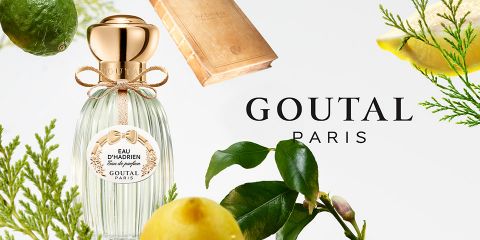 Der Eau d'Hadrien-Parfümflakon von Goutal Paris ist von Zitrusfrüchten und grünen Blättern umgeben, die sich vor einem hellen Hintergrund abheben. Das Logo von Goutal Paris ist gut sichtbar neben dem Flakon angebracht.