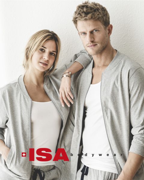 Eine Frau und ein Mann stehen nebeneinander. Beide tragen passende graue Sweatshirts über weißen Oberteilen und grauen Hosen. Die Frau hat ihre Hand auf der Schulter des Mannes. Unten im Bild ist das Logo von „ISA Bodywear“ zu sehen.