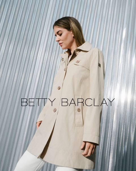 Eine Frau in einem beigen Trenchcoat steht vor einem metallisch gewellten Hintergrund. Der Mantel hat große Knöpfe und einen Kragen. Der Text „Betty Barclay“ ist über das Bild gelegt. Sie wirkt zufrieden und blickt nach rechts.