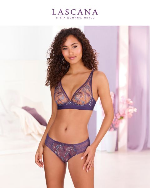 Eine Frau mit lockigem Haar modelliert einen lilafarbenen Spitzen-BH und ein dazu passendes Höschen in einem sanft beleuchteten, eleganten Raum. Über ihr erscheinen das LASCANA-Logo und der Slogan "It's a woman's world".