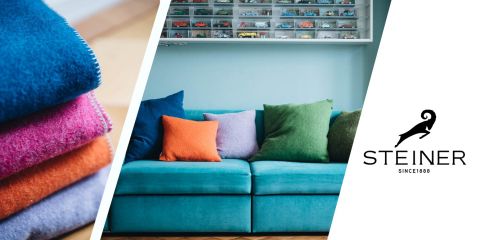Links bunte Stoffmuster, rechts ein blaues Sofa mit bunten Kissen. Über dem Sofa befindet sich ein Regal mit Spielzeugautos. Rechts ist das Steiner-Logo mit der Ziegensilhouette zu sehen.