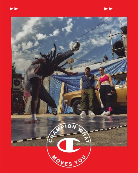 Ein Breakdancer führt im Freien auf einer Matte einen Headspin vor, während ein Mann und eine Frau zuschauen. Sie stehen neben einem Oldtimer vor einer städtischen Kulisse mit blauen Planen und bewölktem Himmel. Ein roter Rahmen mit dem Text und Logo „Champion What Moves You“ umgibt das Bild.