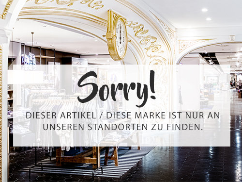 Innenraum eines stilvollen Ladens mit Vintage-Dekor und einer großen Uhr. Eine Meldung im Vordergrund lautet: „Sorry! Dieser Artikel / Diese Marke ist nur an unserem Standorten zu finden“ und weist auf die exklusive Verfügbarkeit im Geschäft hin.