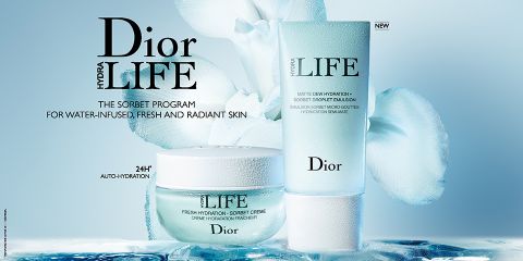 Das Bild zeigt die Hautpflegeprodukte von Dior Hydra Life, darunter ein Tiegel mit frischer Feuchtigkeits-Sorbet-Creme und eine Tube mit matte Tau-Feuchtigkeits-Sorbet-Creme-Emulsion, vor einem sanften blau-weißen Blumenhintergrund. Der Text hebt Merkmale für strahlende Haut hervor.