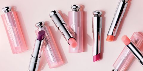 Eine Kollektion von Lippenstiften mit silbernen Kappen und rosafarbenen Hülsen, angeordnet auf einer hellen Oberfläche. Die Lippenstiftfarben variieren und umfassen Schattierungen von Lila, Rosa und Koralle.