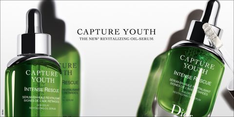 Bild von zwei grünen Flaschen Dior Capture Youth Intense Rescue Revitalizing Oil-Serum. Eine Flasche steht im Vordergrund mit einer silbernen Pipette, eine andere ist im Hintergrund verschwommen. Der Text „Capture Youth“ und Produktdetails sind auf den Flaschen sichtbar.