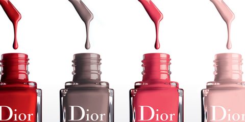 Vier Flaschen Dior-Nagellack in den Farbtönen Rot, Grau, Pink und Nude werden in einer Reihe gezeigt. Tropfen des Lacks tropfen von oben herab, passend zu den Farben der Flaschen. Das Dior-Logo ist auf den Flaschen sichtbar.