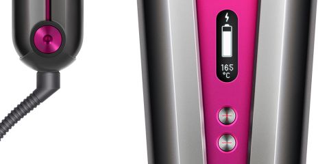 Nahaufnahme eines Haarstyling-Tools mit einer rosa Digitalanzeige, die die Temperatur bei 165 °C und den Batteriestand anzeigt. Das Bild zeigt auch einen Teil der kabelgebundenen Basis.