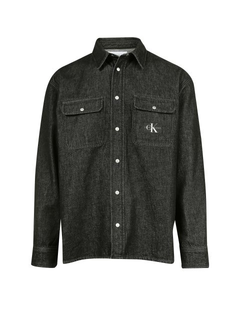 Ein schwarzes Jeanshemd mit zwei Brusttaschen und silbernen Knöpfen. Auf der linken Tasche befindet sich ein kleines weißes „CK“-Logo.
