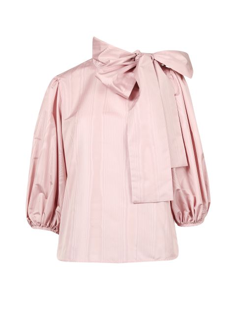 Eine hellrosa Bluse mit langen Puffärmeln und einer großen Schleife am Ausschnitt. Der Stoff hat eine dezente Streifenstruktur und die Ärmel sind an den Manschetten gerafft. Die Bluse ist vor einem weißen Hintergrund zu sehen.
