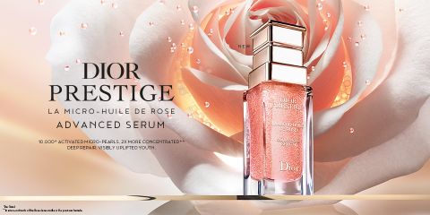 Eine Flasche Dior Prestige Advanced Serum steht vor einer großen Rose. Der Text hebt es als Mikro-Rosenöl mit 10.000 aktivierten Mikroperlen hervor, das eine tiefe Regeneration und jugendliche Haut fördert.