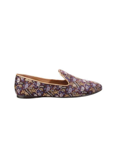 Eine Seitenansicht eines Slipper mit lebhaftem Paisleymuster. Der Schuh hat ein elegantes Design mit spitzer Spitze und ist mit komplizierten blauen, gelben und violetten Mustern auf einem satten kastanienbraunen Hintergrund verziert. Die Sohle ist schwarz und das Futter scheint hellbraun.