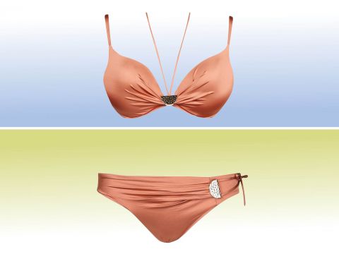 Ein zweiteiliges Bikini-Set vor einem Hintergrund mit Farbverlauf. Das Oberteil ist orange mit Neckholder und Schmucksteinen in der Mitte, während das Unterteil orange mit einer seitlichen Schleife und einem dekorativen Emblem an der Taille ist.