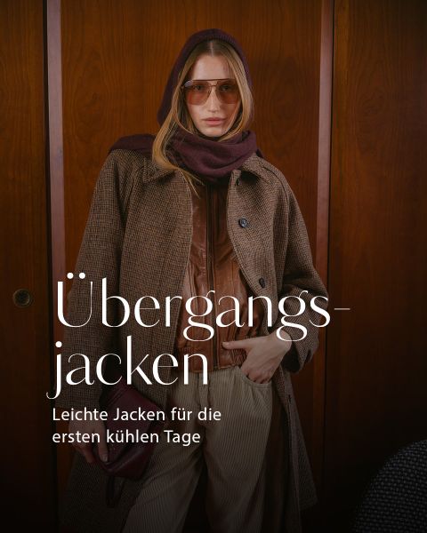 Eine Frau mit Sonnenbrille und mehreren übereinander getragenen Jacken posiert in einem Innenraum. Der deutsche Text lautet: „Übergangsjacken. Leichte Jacken für die ersten kühlen Tage.“.
