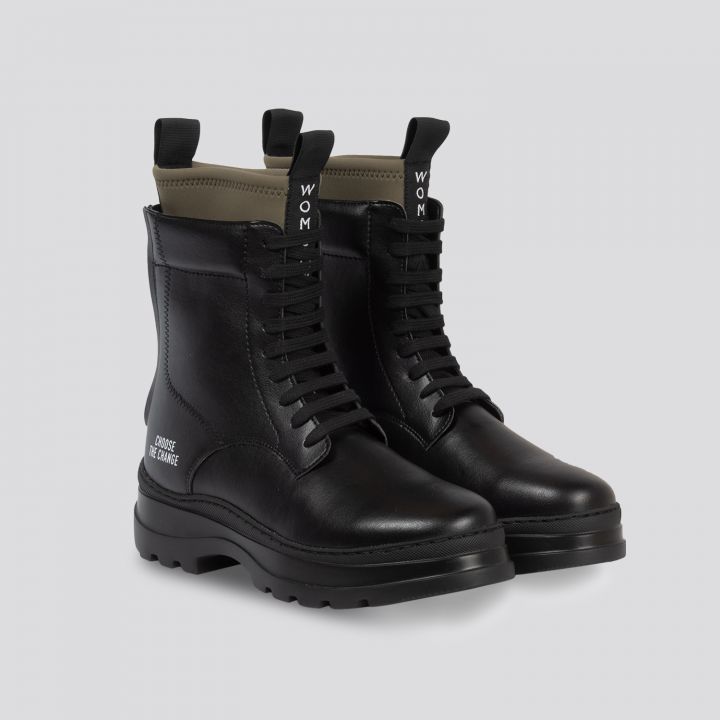 Ein Paar schwarze Schnürstiefel aus Leder mit dicker Sohle und knöchelhohem Design. Auf der Rückseite befindet sich eine Aufreißlasche mit der Aufschrift „WON“ und auf der Außenseite ist „CHANGE THE CHANGE“ in Weiß aufgedruckt. Die Stiefel sind auf einem hellgrauen Hintergrund zu sehen.