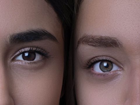 Nahaufnahme der Gesichter zweier Personen nebeneinander, auf der ihre Augen und Augenbrauen zu sehen sind. Die linke Person hat dunkle Augen und Augenbrauen, während die rechte Person hellere Augen und Augenbrauen hat. Beide haben glatte Haut und natürliches Make-up.