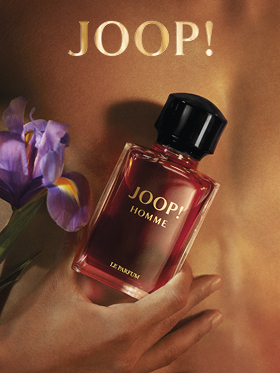 Eine Flasche JOOP! Homme Le Parfum wird vor einem unscharfen Hintergrund mit einer violetten Irisblüte gehalten. Das goldene Logo von „JOOP!“ ist oben deutlich zu erkennen. Das Bild vermittelt Eleganz und Luxus.