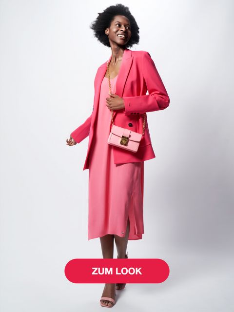 Eine lächelnde Frau in einem rosa Kleid und einem dazu passenden Blazer hält eine rosa Handtasche. Sie posiert selbstbewusst vor einem hellgrauen Hintergrund und am unteren Bildrand befindet sich ein „Zum Look“-Button.