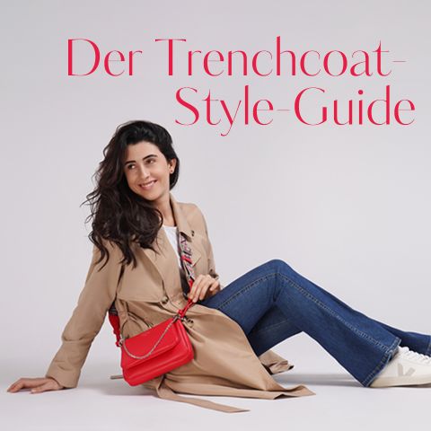 Lächelnde Frau sitzt auf dem Boden, trägt einen beigen Trenchcoat und Jeans und hält eine rote Handtasche. Text lautet „Der Trenchcoat-Style-Guide“.