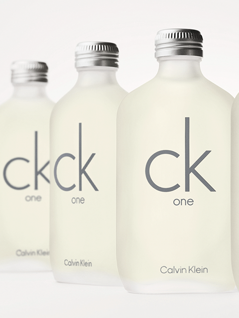 Vier mattierte Flaschen von Calvin Klein CK One sind vor einem hellen Hintergrund zu sehen. Die Flaschen tragen den grauen „ck one“-Schriftzug und silberne Verschlüsse.
