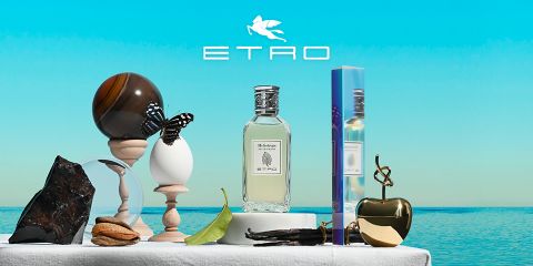 Parfümflakon mit der Aufschrift „ETRO“ und einem Tannenzapfen-Design, umgeben von künstlerischem Dekor: eine Kugel, ein Ei mit einem Schmetterling, ein Stein, ein Blatt, Walnüsse, ein goldener Apfel und eine geformte Hand. Oben das ETRO-Logo vor einem Hintergrund aus blauem Himmel und Meer.