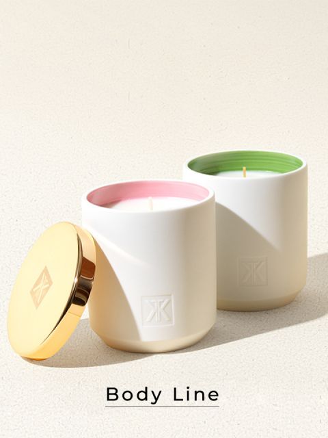 Zwei elegante weiße Kerzen mit strukturierten Deckeln. Die Innenseite einer Kerze ist rosa, die andere grün. Sie stehen auf einer strukturierten Oberfläche und darunter steht der Schriftzug „Body Line“.