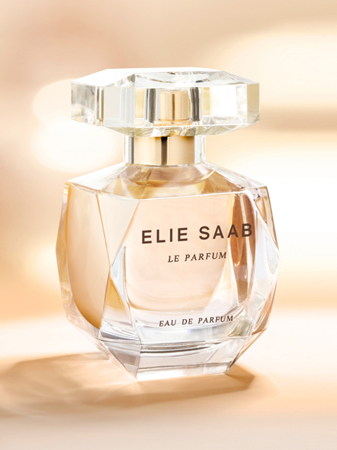 Vor einem weichen, verschwommenen Hintergrund ist ein luxuriöser Parfümflakon mit der Aufschrift „Elie Saab Le Parfum“ zu sehen. Der Flakon ist elegant, aus klarem Glas mit geometrischem, facettiertem Design und enthält eine goldene Flüssigkeit.