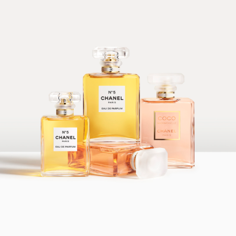 Vier Chanel-Parfümflakons, darunter zwei No. 5 Eau de Parfum mit goldener Flüssigkeit und zwei Coco Mademoiselle, sind auf einer weißen Fläche angeordnet. Die Parfüms befinden sich in eleganten Glasflakons mit quadratischen Verschlüssen, die weiche Schatten werfen.