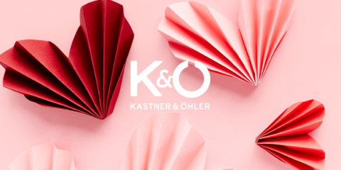 Rote und rosa Papierherzen auf hellrosa Hintergrund mit dem Text „K&Ö Kastner & Öhler“ in der Mitte.