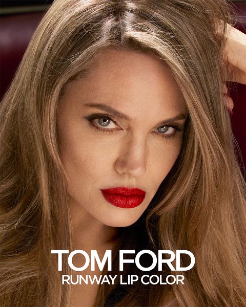 Eine Person mit langen Haaren und knallrotem Lippenstift starrt aufmerksam. Das Bild ist eine Werbung für Tom Ford Runway Lip Color, wobei der Produktname in weißer Schrift unten angezeigt wird.