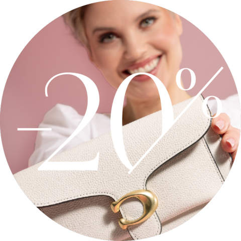 Lächelnde Frau hält eine beige Handtasche mit goldenem Verschluss vor rosa Hintergrund. Der weiße Text über dem Bild lautet „-20%“, was auf einen Rabatt von 20 % hindeutet.