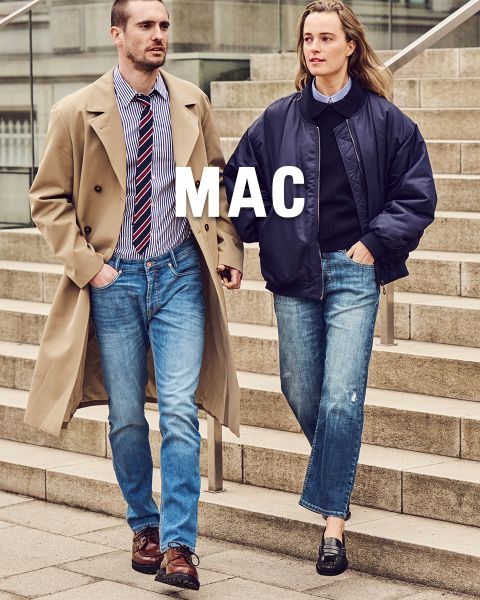 Ein Mann im Trenchcoat und eine Frau in einer marineblauen Jacke gehen in Bluejeans eine Steintreppe hinunter. Über dem Bild ist der Schriftzug „MAC“ zu sehen.