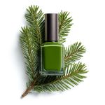 Eine Flasche mit grünem Nagellack steht auf frischen Tannenzweigen vor einem weißen Hintergrund.