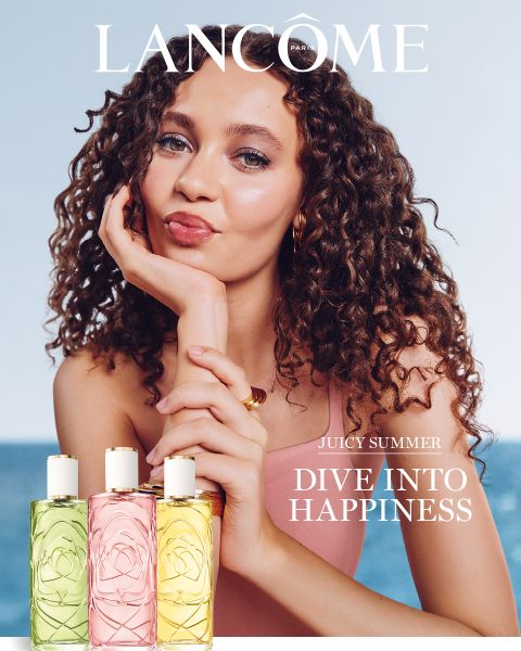 Eine Frau mit lockigem Haar stützt ihr Kinn auf die Hand und lächelt. Unter ihr stehen drei bunte Lancôme-Parfümflakons. Der Text lautet: „Lancome. Juicy Summer. Tauche ein ins Glück. Jetzt entdecken.“.