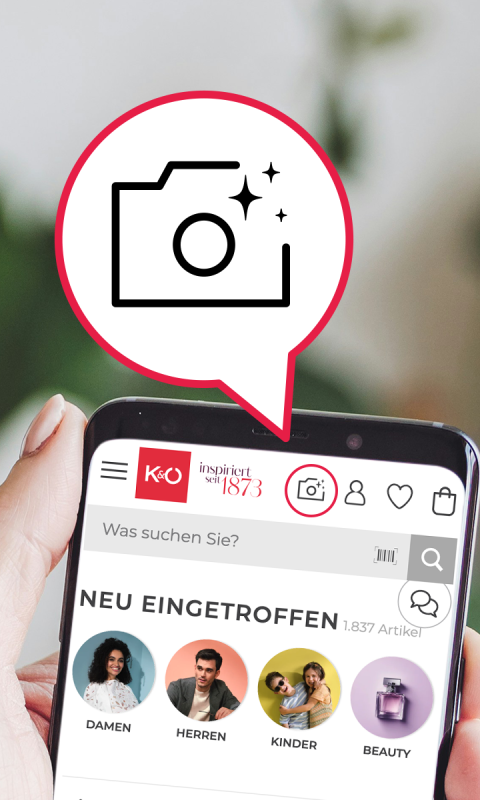 Eine Hand hält ein Smartphone, auf dem eine Shopping-App auf Deutsch angezeigt wird. Diese zeigt eine visuelle Suchfunktion mit der Option, ein Foto hochzuladen oder aufzunehmen, um ähnliche Produkte zu finden.