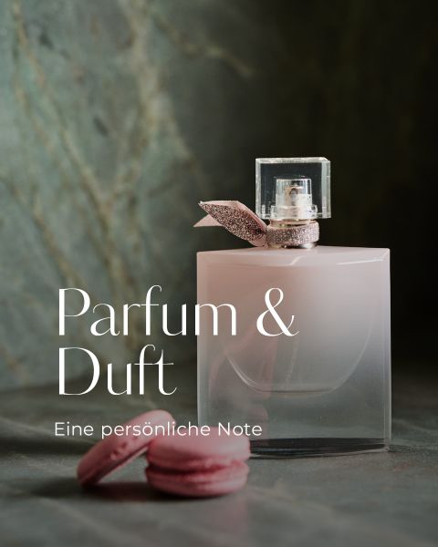 Ein rosafarbener Parfümflakon mit einem Glitzerband steht neben zwei rosafarbenen Macarons auf einer grauen Fläche. Der Hintergrund besteht aus grünem Stein mit Textur. Der Text lautet: "Parfum & Duft. Eine persönliche Note.".