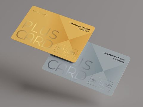 Zwei transparente Karten schweben vor grauem Hintergrund. Eine ist golden mit dem Text „PLUS CARD“, die andere hellblau mit dem gleichen Design. Beide tragen den Namen „Marianne Muster“ und darunter Zahlen.
