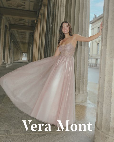 Eine Frau in einem fließenden, schulterfreien rosa Kleid posiert anmutig vor einer Säule in einem Außenkorridor. Unten ist der Text „Vera Mont“ zu sehen. Die Kulisse ist im klassischen Architekturstil mit Säulenreihen gehalten.