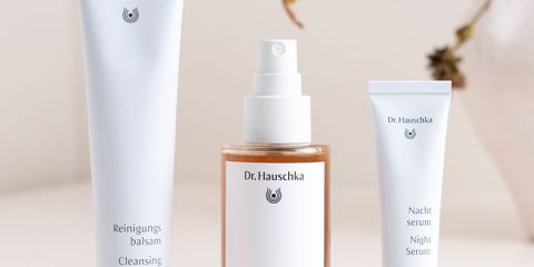 Das Bild zeigt verschiedene Hautpflegeprodukte von Dr. Hauschka, darunter Cremes und Öle, sowie natürliche Elemente wie Blumen und Samen. Der Text lautet: „100 % zertifizierte Naturkosmetik. Natürlich. Anders. Wirksam.“.