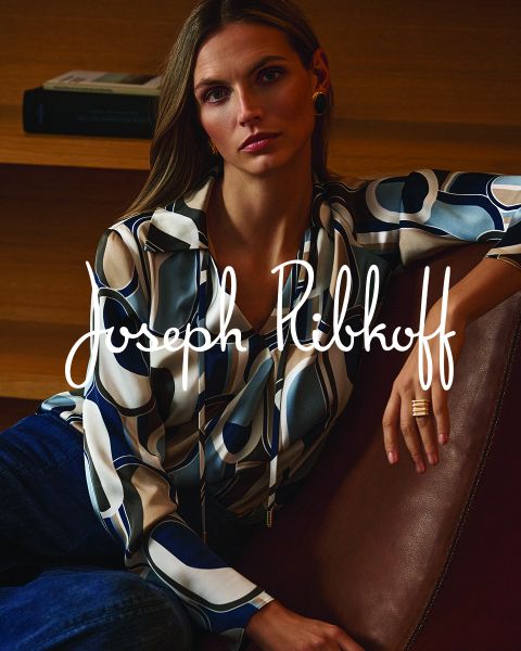 Eine Frau in einer gemusterten Bluse und Jeans sitzt auf einem Ledersofa; über das Bild ist in weißer Schrift „Joseph Ribkoff“ geschrieben.