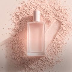 Ein Parfümflakon aus klarem Glas mit einer blassrosa Kappe steht auf rosa Puder, daneben ist ein Häkchen in den Puder gepinselt.