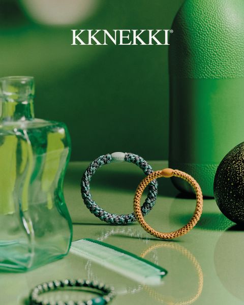 Eine Person in einem marineblauen Pullover und Jeans hält eine blaue Haarbürste hinter ihrem Rücken und trägt türkisfarbene Perlenarmbänder. Darüber das Logo "KKNEKKI".