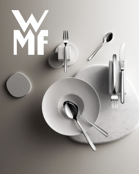 Ein mit Feigen, Brombeeren und aromatischen Garnituren gefüllter Kochtopf steht auf einem dunklen Holzbrett. Über dem Kochtopf ist das WMF-Logo zu sehen. Der Hintergrund ist eine strukturierte dunkle Oberfläche.