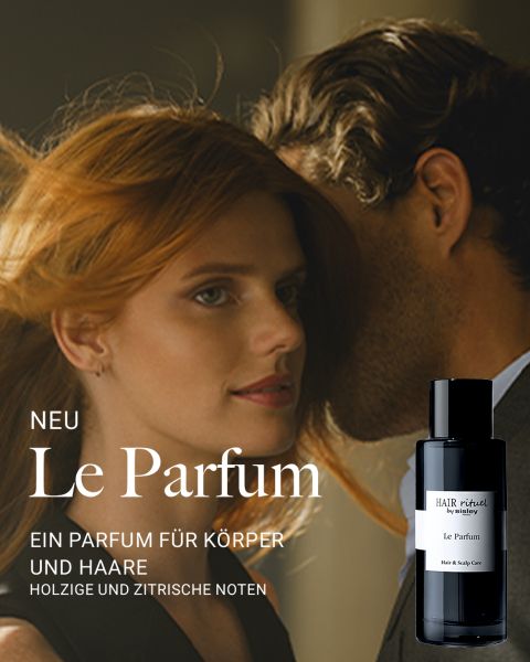 Eine rothaarige Frau blickt nach vorne, während ein Mann ihr etwas ins Ohr flüstert. Im Vordergrund steht ein schwarzer Flakon mit der Aufschrift "Le Parfum" von Hair Rituel. Der Text beschreibt es als ein neues Parfüm für Körper und Haar mit holzigen und zitrischen Noten.