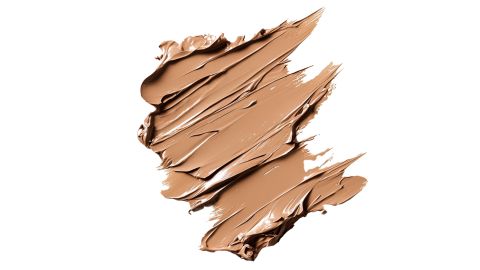 Ein glatter, cremig-beiger Fleck Make-up-Grundlage auf weißem Hintergrund, der ein strukturiertes Muster mit unebenen Kanten und sichtbaren Pinselstrichen aufweist.