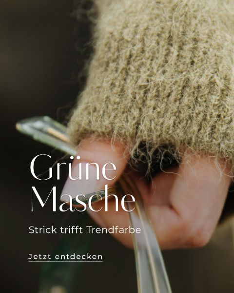 Nahaufnahme einer Hand, die einen dicken grünen Strickpullover trägt und Stricknadeln hält. Der überlagerte Text in Deutsch lautet: "Grüne Masche. Strick trifft Trendfarbe. Jetzt entdecken.