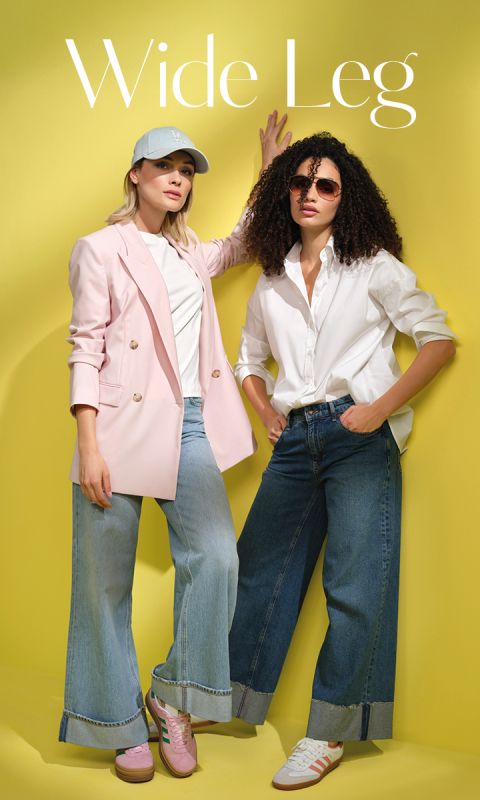 Zwei Models in Wide-Leg-Jeans stehen vor einem gelben Hintergrund. Eines trägt einen rosa Blazer, ein weißes Top, rosa Sneakers und eine Cap. Das andere trägt ein weißes Shirt, eine Sonnenbrille und Sneakers. Oben steht der Schriftzug „Wide Leg“.
