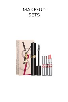 Ein Make-up-Set von Yves Saint Laurent mit einer Schachtel, einer schwarzen Mascara-Tube mit goldenem YSL-Logo und einem silbernen Lippenstift mit einem rosa Farbton, alles auf weißem Hintergrund mit dem Text „MAKE-UP SETS“ darüber.